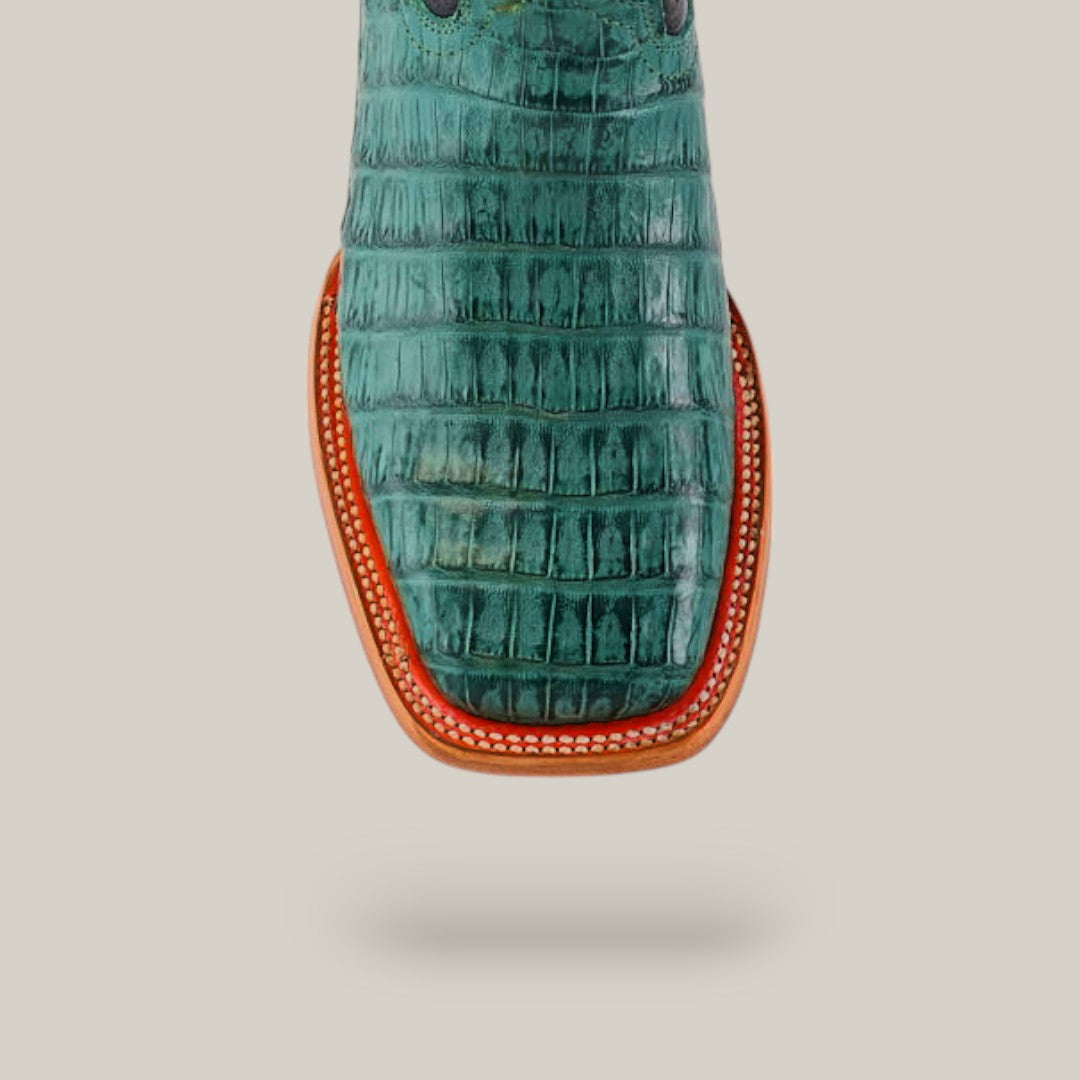 A top view showcases the Exotic Caiman Belly Tail boot in green with a square toe, featuring premium caiman leather. The tan leather sole with red trim and white stitching contrasts against a light gray backdrop, highlighting its exotic pattern.