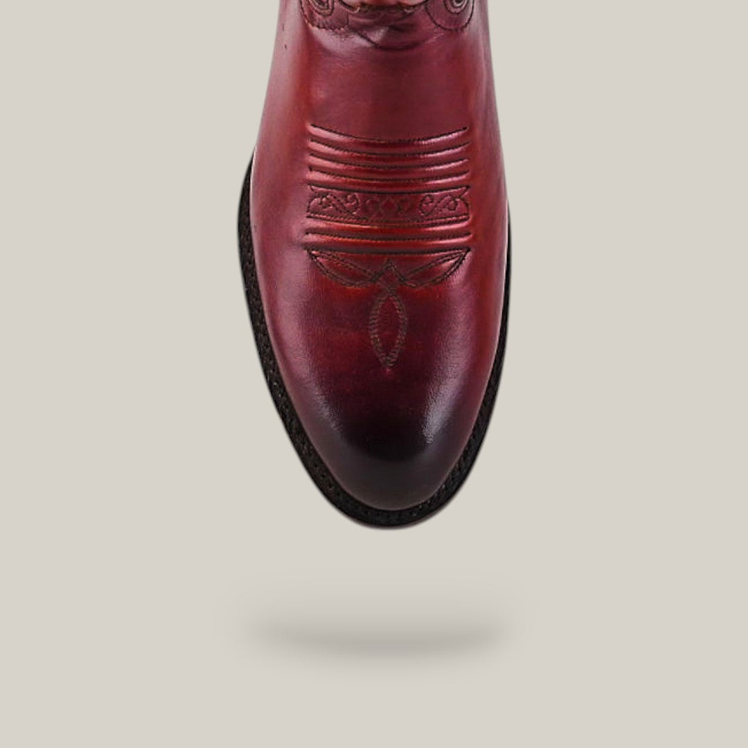 A top view of the Wyatt - Cogñac - Roper Toe boot, a reddish-brown cowhide design featuring decorative toe stitching, highlights its quality craftsmanship against a plain light background.