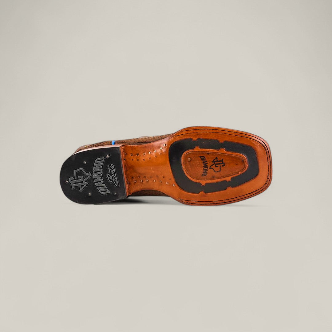 The image displays the sole of the Exotic Python - Tamarindo - Square Toe boot in brown leather with a black heel, showcasing branding and textured patterns on the heel and midsection against a plain light background.