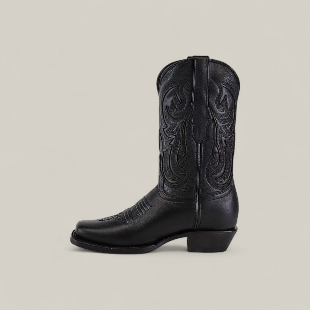 The Josie Full Black boot features a short shaft, narrow square toe, chic black leather with decorative stitching, and a low angled heel, shown against a plain light background.
