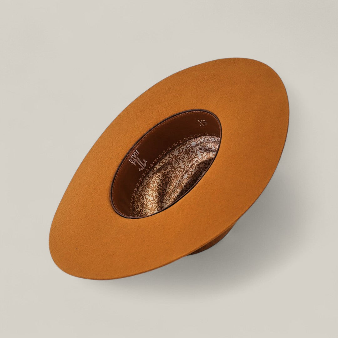The 4X Caramel - TC Hats is a wide-brimmed, brown open crown Texana hat shown from above, featuring a patterned silk lining and an interior leather decorative band against a plain, light background.