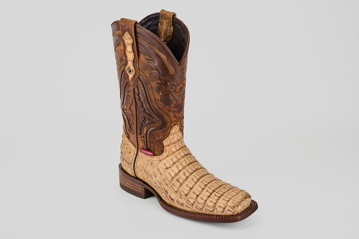 The Exotic Caiman Hornback - Orix - Rodeo Toe is a handcrafted cowboy boot with a tan, alligator-patterned foot, dark brown stitched leather shaft, square toe, and low heel—an elegant exotic boot shown on a plain light background.