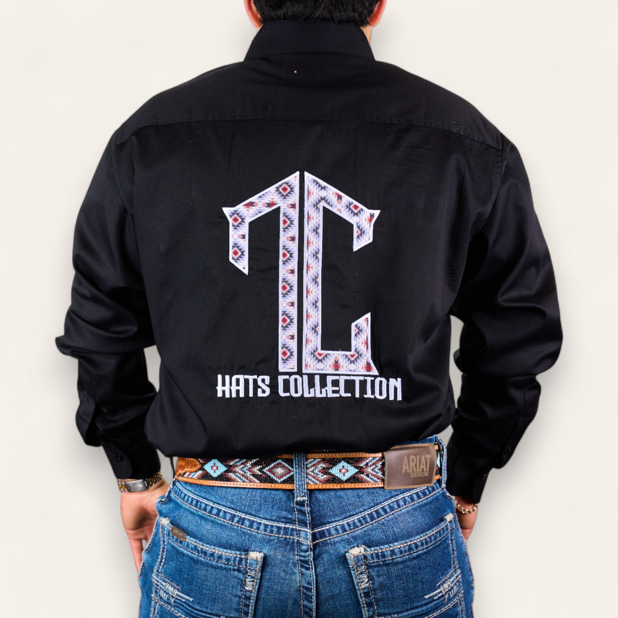 Someone wearing the TC Hats - Black Red Aztec shirt with a patterned TC logo embroidered on the back, styled with blue jeans and a matching patterned belt.