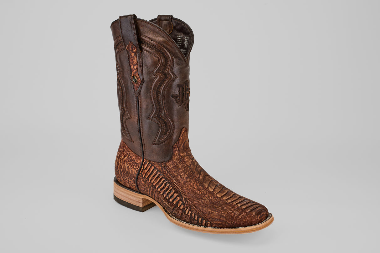 A single Exotic Full Quilt Ostrich Leg cowboy boot in Rustic Brick with a square toe and a wooden stacked heel, featuring intricate patterns, displayed on a plain gray background.