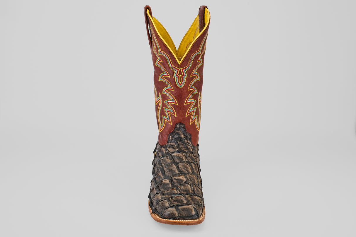A single Butch - Caramel - Square Toe cowboy boot with a textured dark brown Pirarucu leather foot and a tall red shaft featuring yellow and beige stitching, viewed from the front against a plain light background.