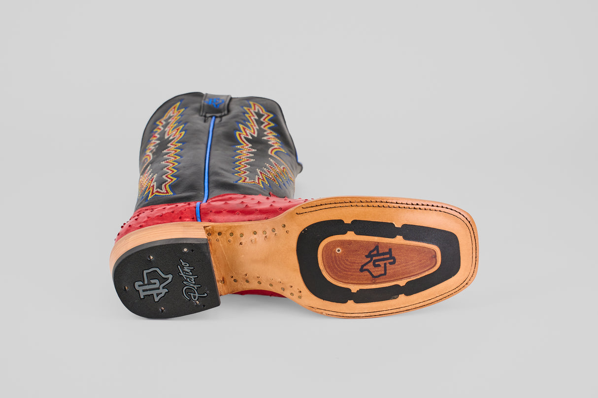 The Crowley - Red - Square Toe cowboy boot lies on its side, showing the leather and rubber sole. The upper features black and red leather with yellow decorative stitching and blue piping.