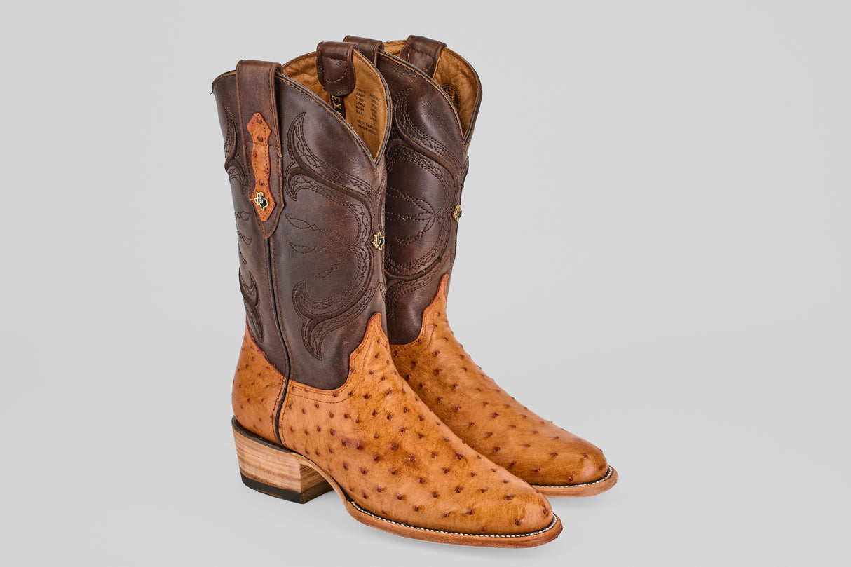 The Austin - Brandy - Roper Toe boots are men's cowboy boots with light brown textured ostrich leather foot, dark brown smooth leather shaft, decorative stitching, wooden heels, and classic roper toe styling.