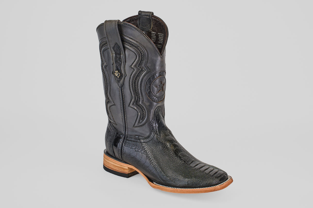The Austin Leg - Black - Square Toe cowboy boot features detailed stitching, a star emblem, textured ostrich leather, pull straps, and a wooden sole, shown against a simple light gray background.
