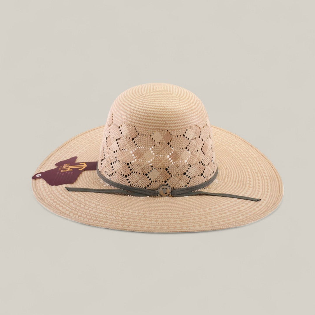 The 30X Hexagon - Open Crown is a beige wide-brimmed straw hat with a patterned perforated crown, grey band featuring a round emblem, and maroon tag on the brim, shown against a neutral background.