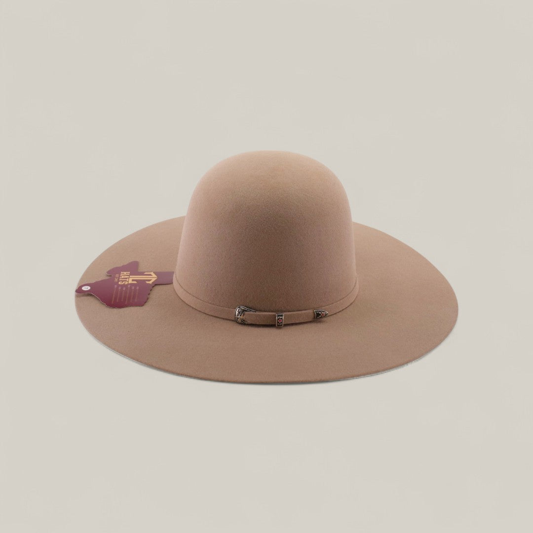 The 4x - Natural - TC Hats is a wide-brimmed, light brown felt Western hat with an open crown, a small decorative band, and a maroon tag on the brim, shown against a plain, light background.