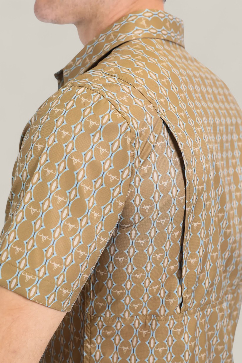 A close-up side view of a person wearing the Mens Performance Western Short Sleeve Aztec Print Camel Shirt (PGW10645), featuring short sleeves and a zippered side vent that opens to reveal the mesh lining underneath.