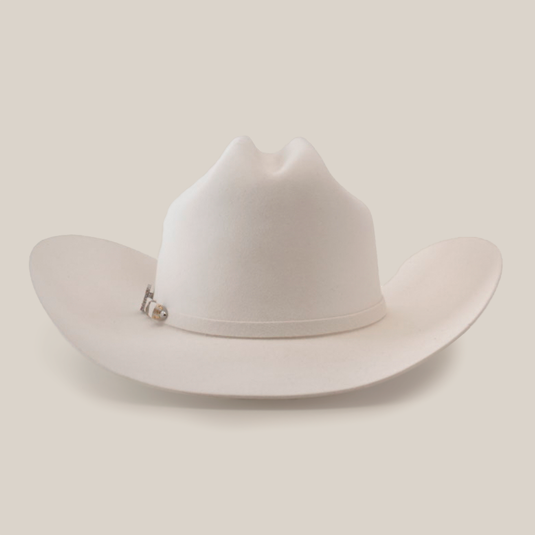 The 10X Jerarca White is a white cowboy hat made from premium fur felt, featuring a wide brim and distinctive crown crease. Adorned with a small decorative band, this classic western headwear embodies timeless style against a minimalist backdrop, highlighting its refined design.