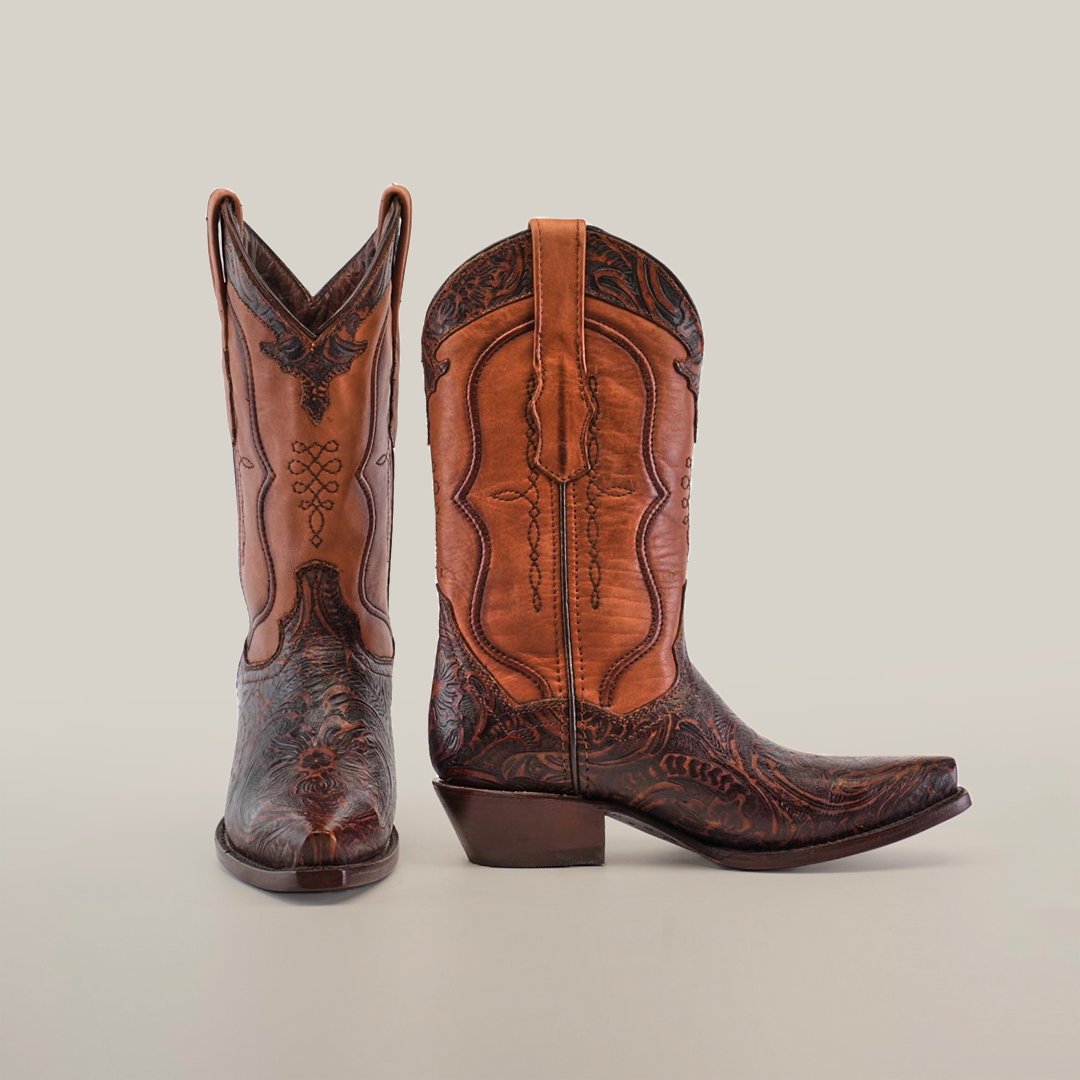 A pair of intricately designed brown cowboy boots with ornate patterns, displayed on a plain light background. One boot faces forward, while the other is angled sideways, showcasing the side details.