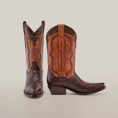 A pair of intricately designed brown cowboy boots with ornate patterns, displayed on a plain light background. One boot faces forward, while the other is angled sideways, showcasing the side details.