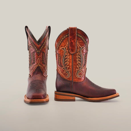 A pair of brown cowboy boots with intricate patterns on a neutral background. The left boot faces forward, while the right boot is turned to the side, highlighting the detailed stitching and design.