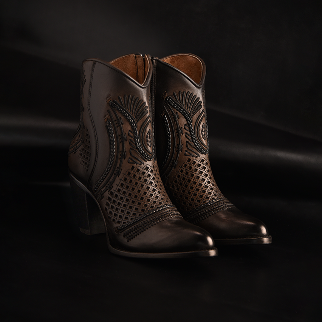 The Maple Shading Laser & Embroidery & Woven - Round Toe boots are elegant black leather ankle boots with intricate embroidery and high heels, showcased against a dark background for added sophistication.