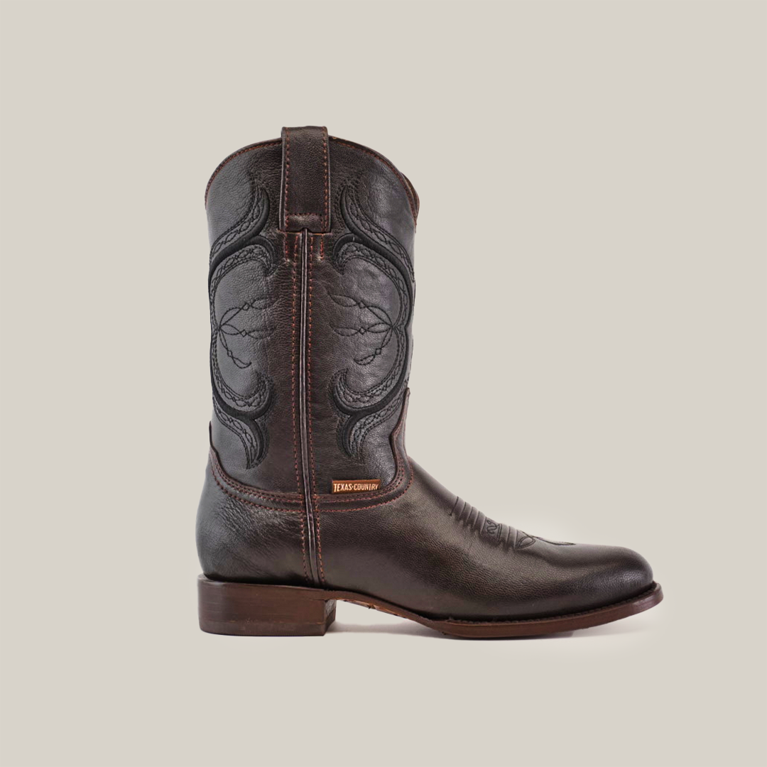 The Rush Brown - Roper Toe boot, made from premium cowhide leather, showcases intricate shaft stitching, a slight heel, and a JEANS COMPANY tag. It features a classic Roper Toe design and durable leather sole, displayed on a plain white background.