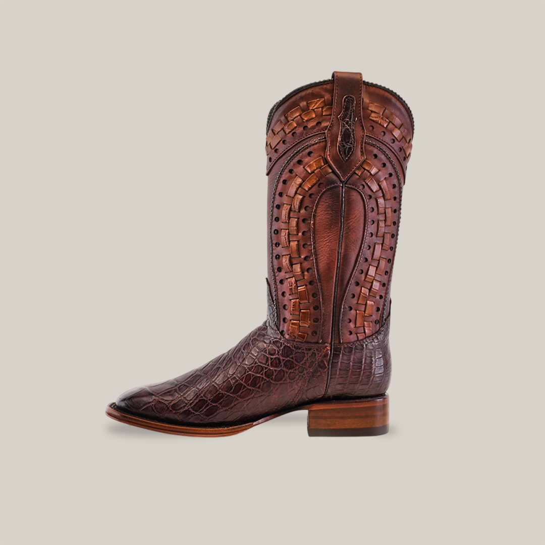 The Exotic American Alligator - Herradura - Tabaco boot, crafted from brown leather with intricate stitching and embossed textures, epitomizes classic Western footwear. It showcases a square toe, mid-calf height, and a small stacked heel against a light gray background.