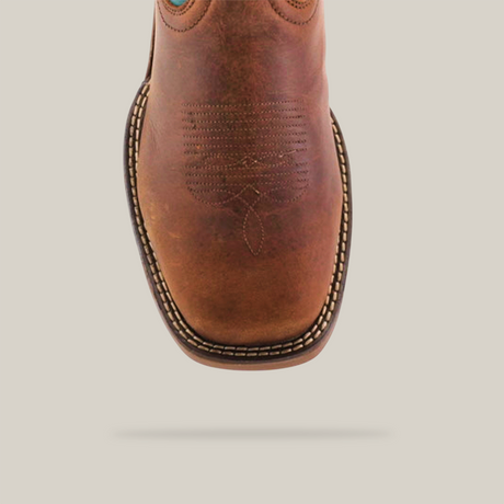 The Rustic Turquoise Brown boot, made from premium cowhide leather, combines a brown foot with a vibrant turquoise shaft featuring intricate stitching, set against a plain white backdrop. Its waterproof and includes a composite toe for added protection.