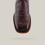 Close-up of the Exotic American Alligator - Herradura - Tabaco boot, showcasing its brown, textured alligator-like pattern and square toe with visible stitching against a plain background.