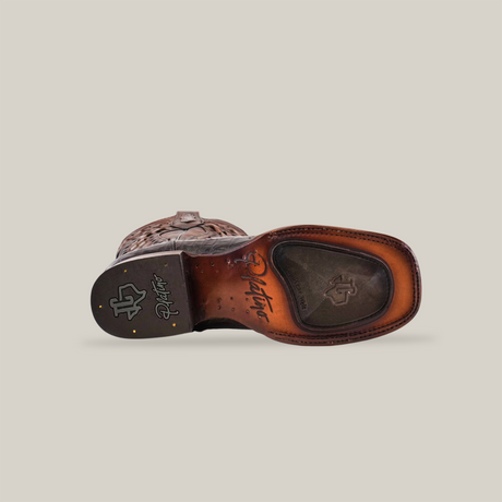 A bottom view of the Exotic American Alligator - Herradura - Tabaco boot displays detailed stitching and branding with Goodyear Welt Construction. The sole, featuring a logo and textured patterns, showcases brown and black treads for grip against a neutral background.