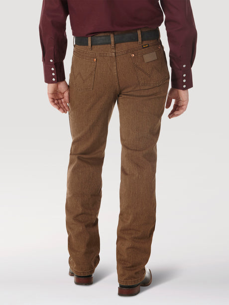 A person in a maroon long-sleeve shirt and brown Wrangler Cowboy Cut Slim Fit Jean - 100936BKW stands with their back to the camera, hands at their sides. The pants have pockets, and the shirts buttoned cuffs perfectly complement the brown shoes.