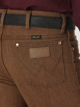 Close-up of a person wearing Wrangler Cowboy Cut Slim Fit Jeans - 100936BKW with a black belt. The jeans feature a branded leather patch above the right pocket and a small tag on the waistband, paired with a dark red shirt for classic style and rugged elegance.