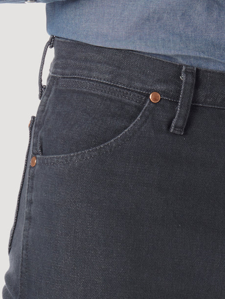 Close-up of someone in Wrangler Cowboy Cut Slim Fit Jeans - 0936CHG, featuring dark denim, visible stitching, and copper rivets on the pocket; paired with a tucked-in blue denim shirt to highlight premium denim quality.