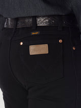 Close-up of a person wearing Wrangler Cowboy Cut Slim Fit Jean - 0936WBK with visible stitching and a branded leather tag, paired with a dark, intricately patterned leather belt.