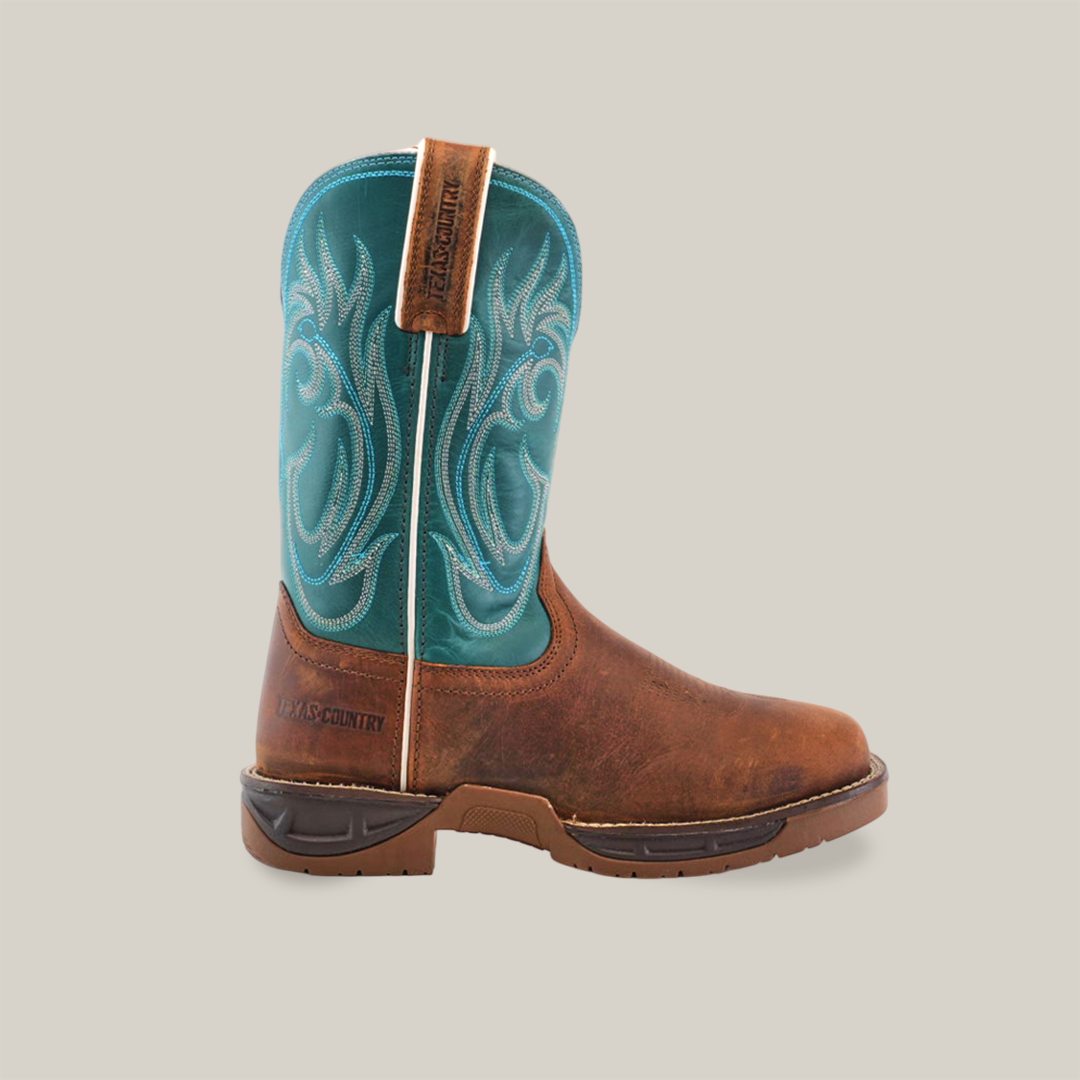 The Rustic Turquoise Brown boot flaunts a brown foot and turquoise shaft with stitched details. Made from premium cowhide leather, it features a tough brown sole and RUGGED COUNTRY pull tab. Positioned sideways on white, its the essence of rugged work boots.
