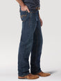 A person stands with one hand in their pocket, wearing dark blue jeans and brown leather shoes. The jeans, Wrangler® 20X® No. 33 Relaxed Straight Leg 1033MWXWL, have visible stitching on the back pocket. The background is plain and light-colored.