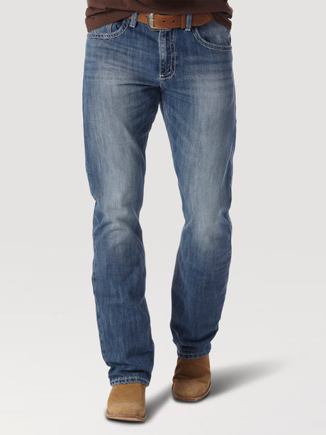 Wearing faded blue Mens Wrangler 20X No. 42 Vintage Bootcut Jean - 1042MWXLB, a person with a brown belt and leather shoes stands against a light background. The premium denim shows slight whiskering and offers a timeless, classic straight fit style.