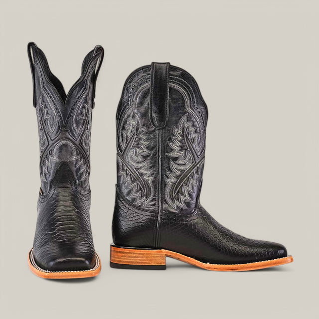 The Python Print Black - Square Toe cowboy boots, with a leather texture and intricate embroidery, display a square toe design. Their wooden heel and sole are highlighted with one boot facing forward and the other to the side against a neutral background.