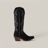 The Kellie Suede Black Leather Sole boot features intricate white stitching, a snip toe, and a brown stacked heel with a small silver emblem. Its leather sole ensures elegance and durability against a plain light gray background.