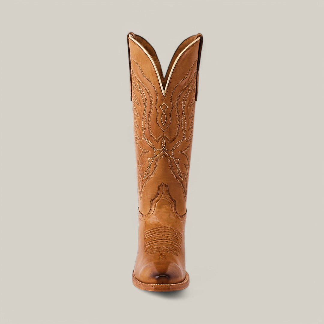 The Miranda Clayton Gold Leather Sole boot features a single tan design with decorative stitching and intricate leaf and swirl patterns on the mid shaft, set against a light gray background. It has a snip toe and is complemented by a luxurious gold leather sole.