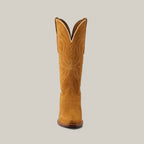 The Miranda Suede boot in gold leather stands upright, showcasing its snip toe, decorative white stitching, tan color, and slightly curved top edge against a plain background.