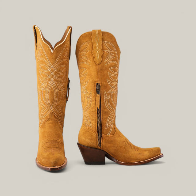 The Kellie Suede Gold Leather Sole boots feature a tall shaft and intricate white stitching on premium tan suede. With a sophisticated snip toe and gold leather sole, the right boot stands upright while the left reveals a side zipper against a neutral gray background.