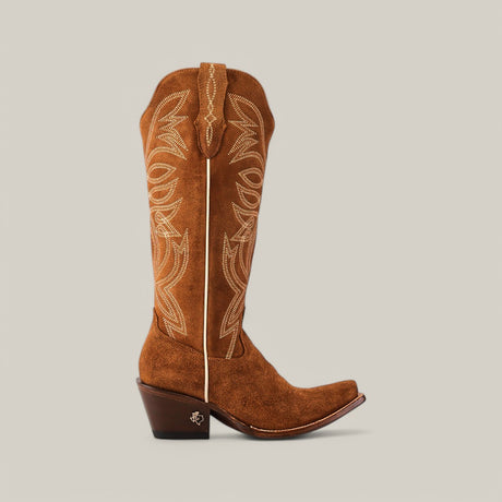 The Kellie Suede Caramel Leather cowboy boot features intricate cream stitching on a plain light background, with a snip toe, mid-height heel, and pull straps.