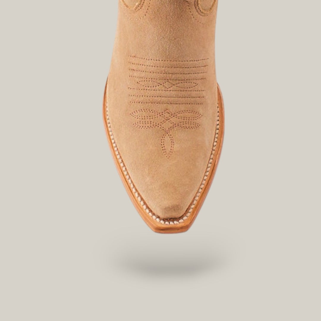 A close-up of the Kellie Suede Fawn boots shows a beige cowboy boot with intricate stitching and a subtle snip toe, positioned against a plain light gray background.