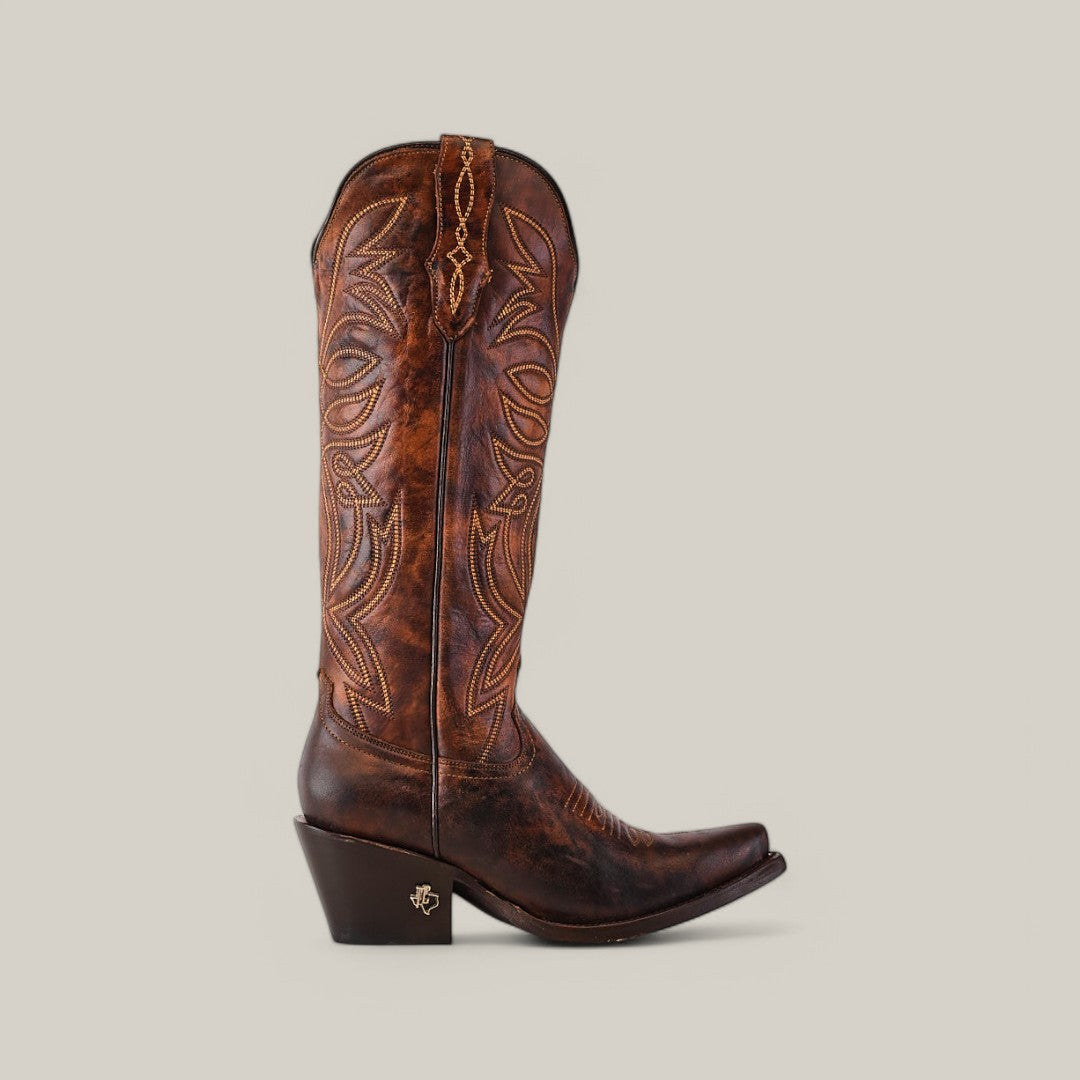 The Kellie Rustic Brown Leather Sole boots feature decorative stitching, a tall shaft, snip toe design, slightly angled heel with a metal emblem, and are set against a plain light background.