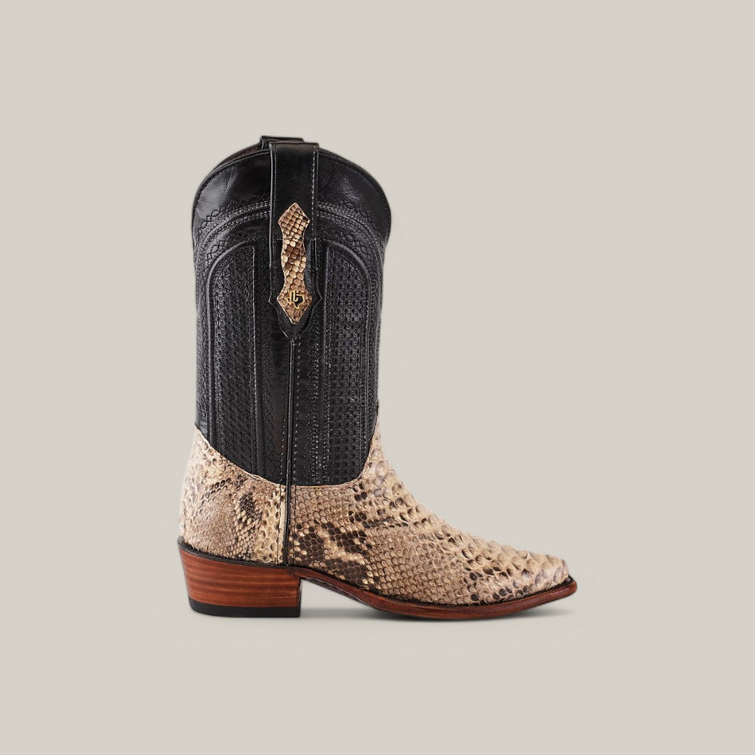 The Exotic Python - Natural - Snip Toe boot boasts a striking two-tone design with a black textured upper, beige python leather lower, short heel, decorative emblem near the top, and classic snip toe.