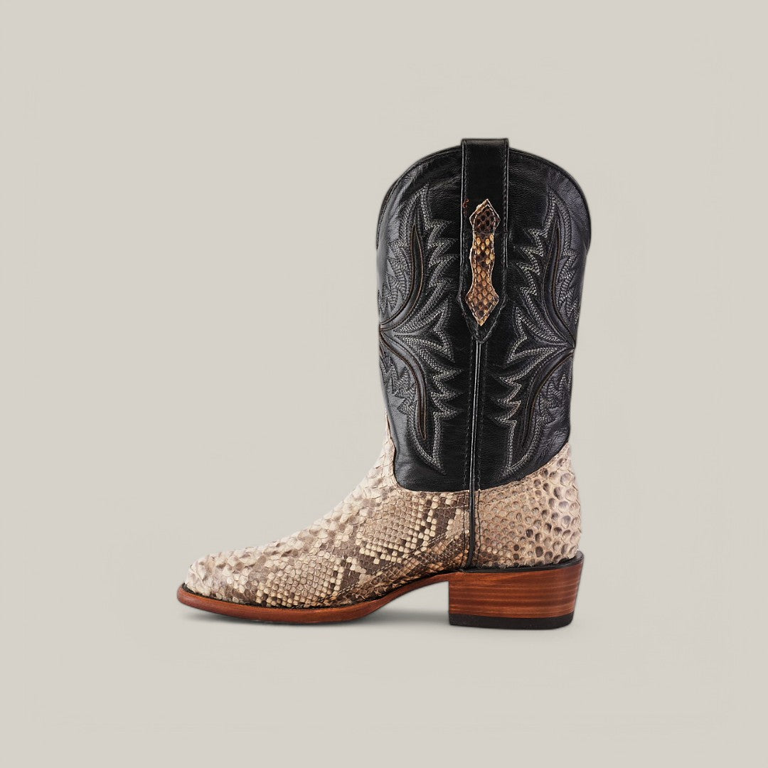 The Exotic Python - Natural - Round Toe boot is a luxury item featuring a light snake pattern on the foot, a sleek black upper with intricate stitching, and a wooden heel. It includes a convenient side pull strap. A plain light gray background highlights its elegance.