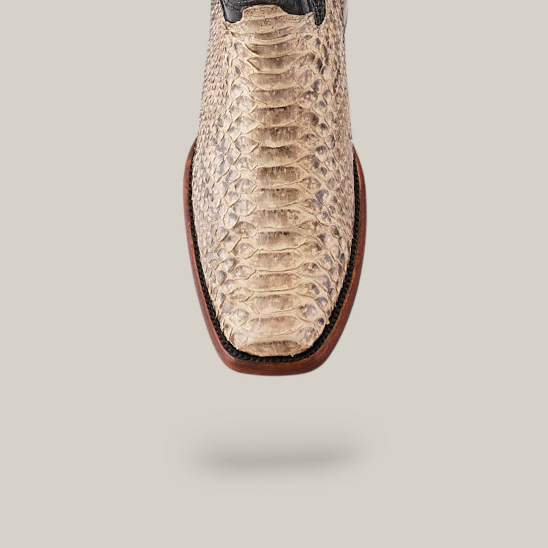 Close-up of the Exotic Python - Natural boot featuring a textured beige and brown snakeskin pattern on a light gray background. With its narrow square toe design, this standout piece is ideal for making an impression.