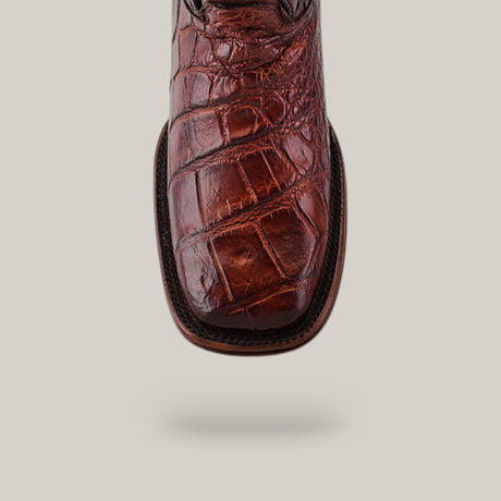 Close-up of the Exotic American Alligator - Herradura - Brandy boot showcasing its square toe design. The authentic leathers intricate patterns stand out against a neutral background.