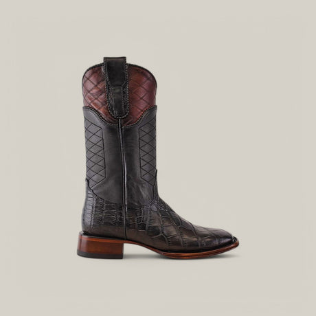 The Exotic American Alligator boot in dark gray boasts exceptional craftsmanship with a crocodile texture and a quilted upper shaft. It features a square toe and wooden heel, presented against a plain beige background.