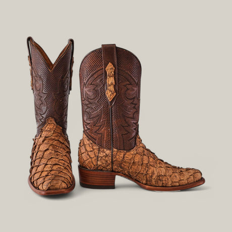 A pair of exotic Pirarucu Fish cowboy boots, featuring intricate dark brown leather uppers and lighter tan textured leather on the lower parts and toes, with a stacked heel in a matte Orix finish, showcased against a plain background.