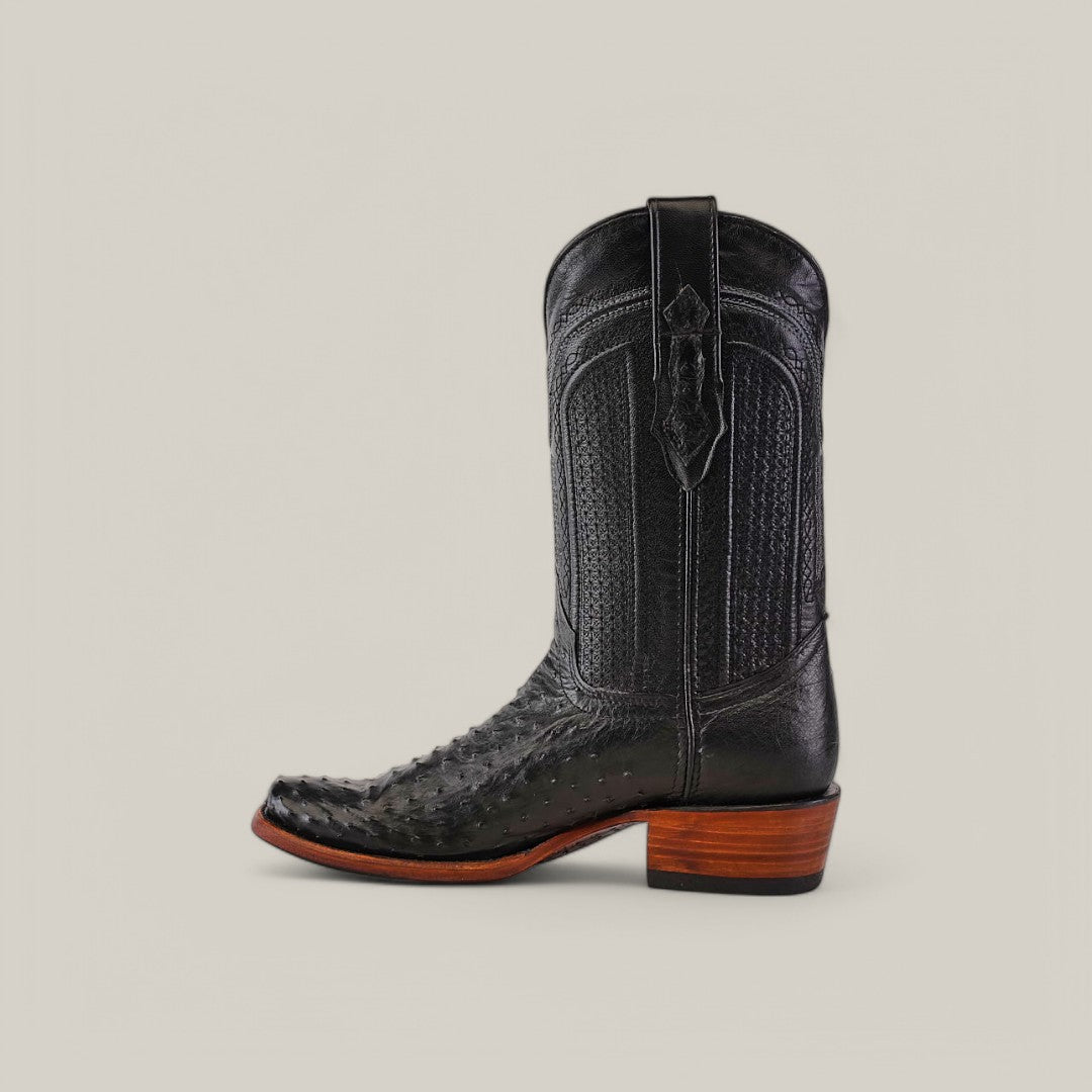 The Exotic Ostrich - Black boots feature genuine leather with a textured pattern and narrow square toe. They include a brown stacked heel and side pull straps, showcasing Western heritage against a plain beige background.