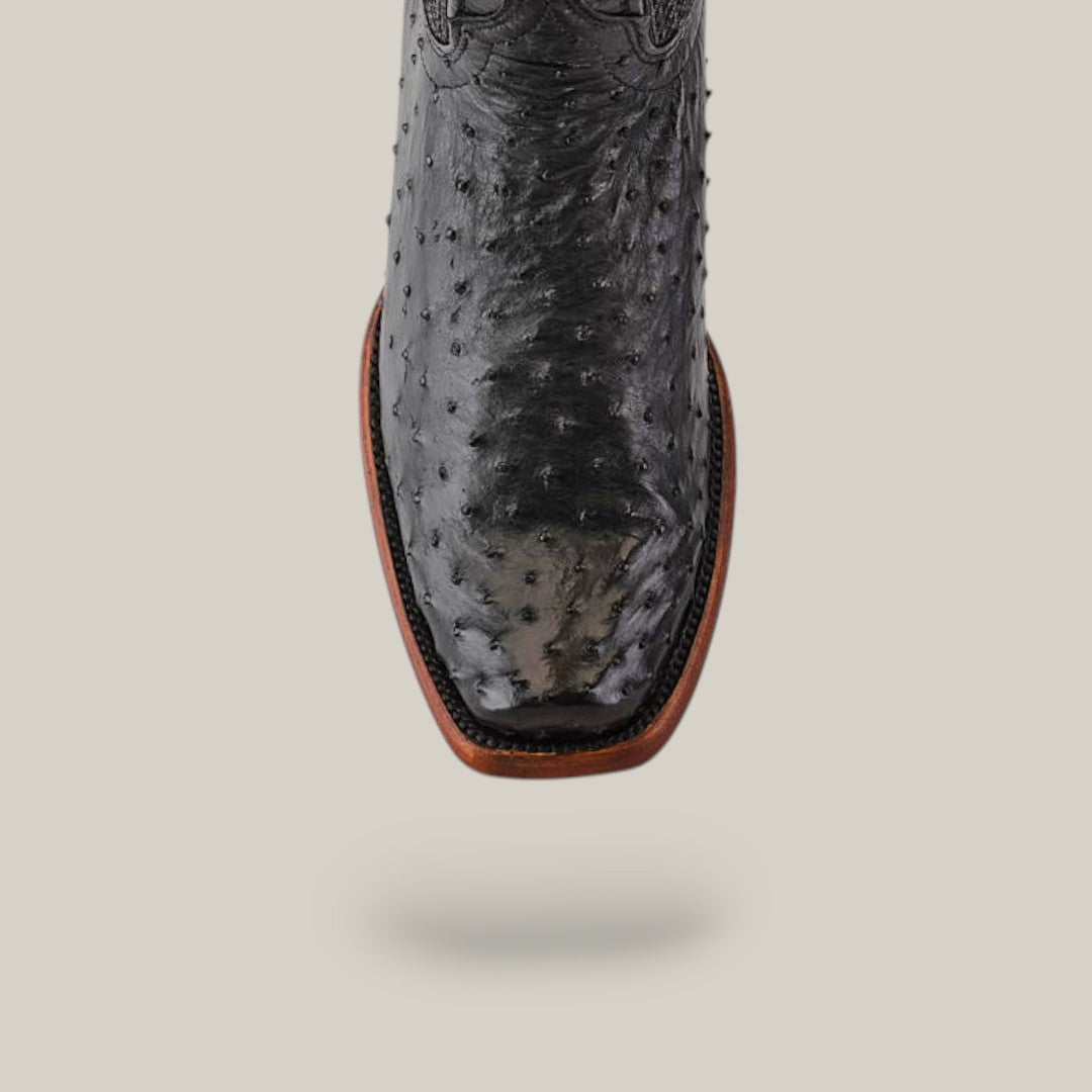 The Exotic Ostrich - Black boot, with a narrow square toe and intricate stitching, showcases its textured genuine leather with distinctive bumpy patterns against a light gray background, reflecting Western heritage.