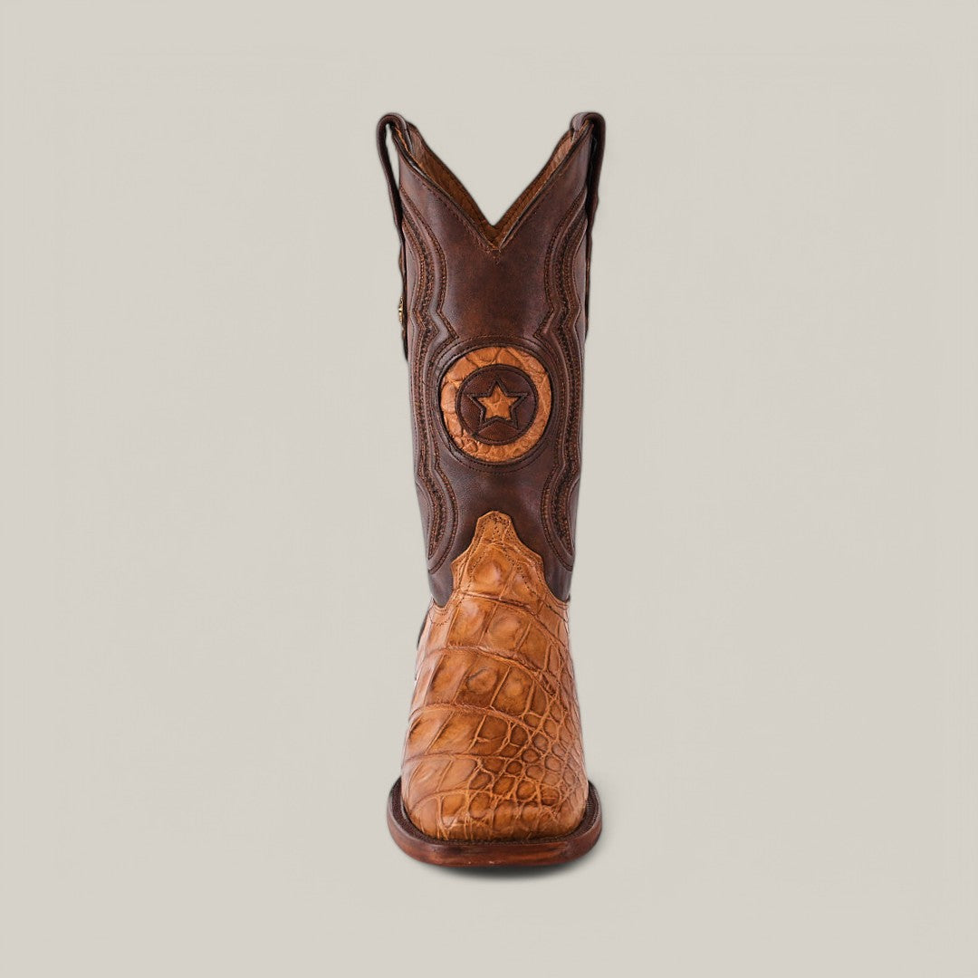 The Exotic American Alligator Hornback - Fawn - Square Toe boot features a brown upper with a star emblem and sophisticated craftsmanship. Its tan, textured lower portion mimics exotic alligator skin, showcased elegantly against a light gray background.