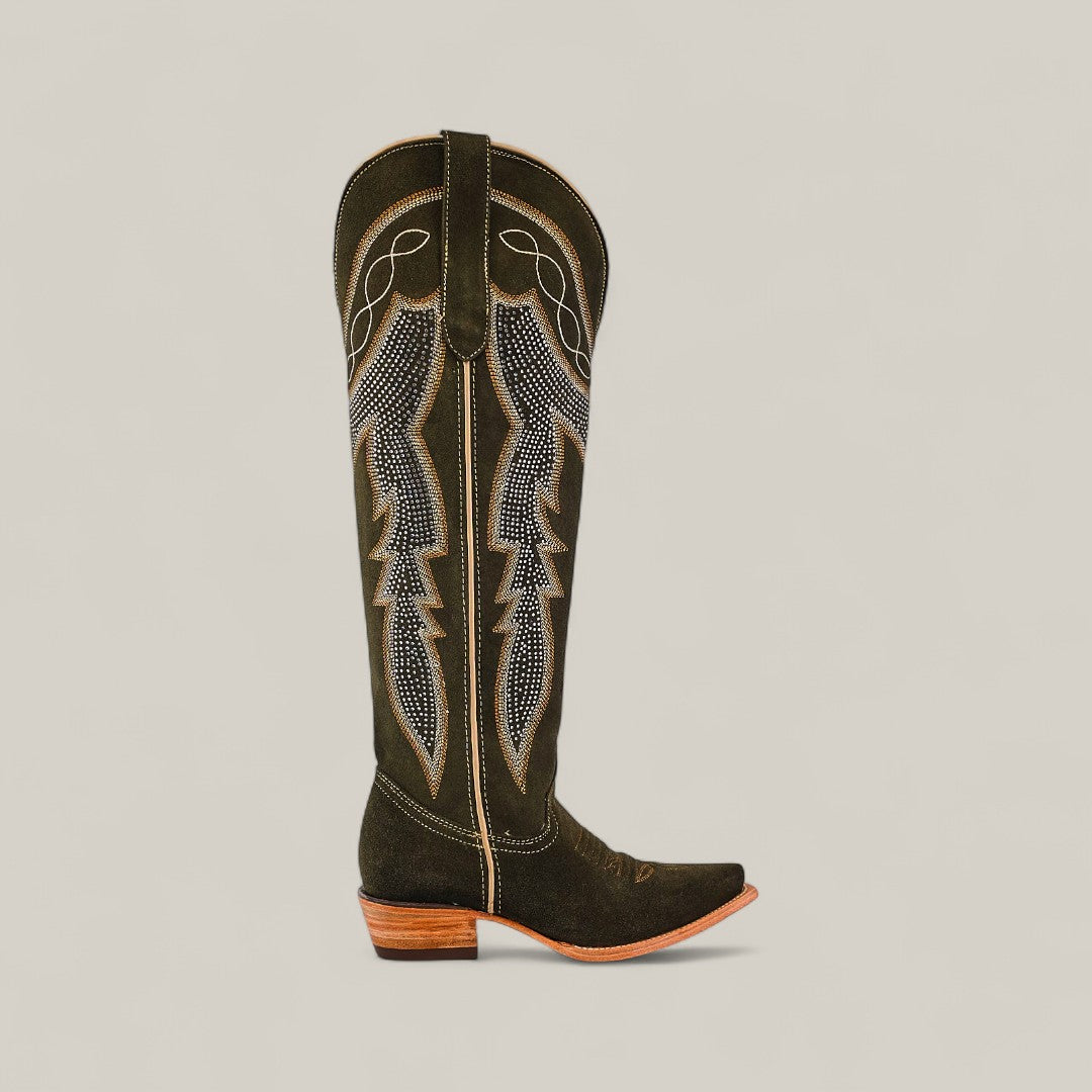 The Della Olive Green boot features a tall shaft, snip toe, decorative stitching on olive green leather, and a low wooden heel, shown against a plain beige background.